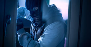 burglar with crowbar to break door to enter the house